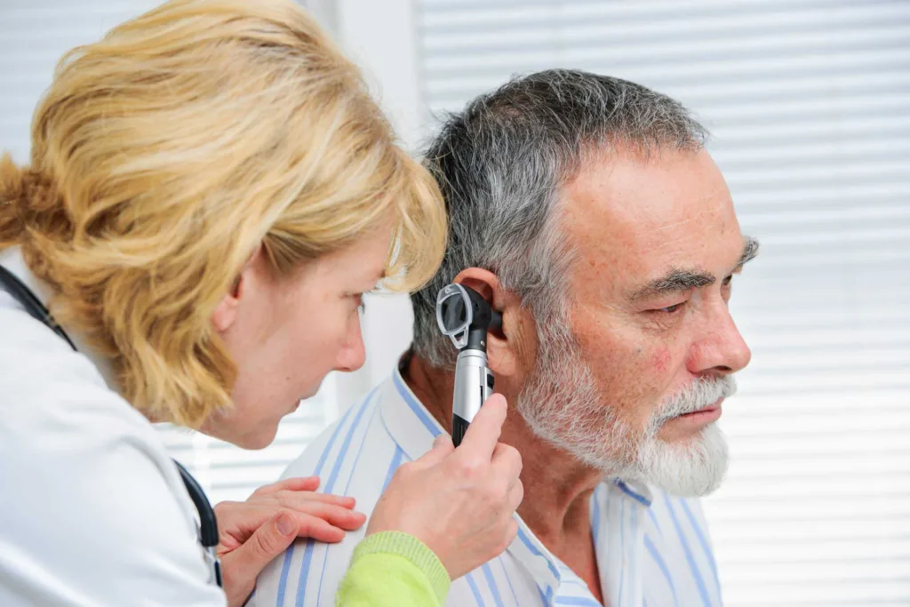 audiologist checks her patient's ears during a quarterly hearing check