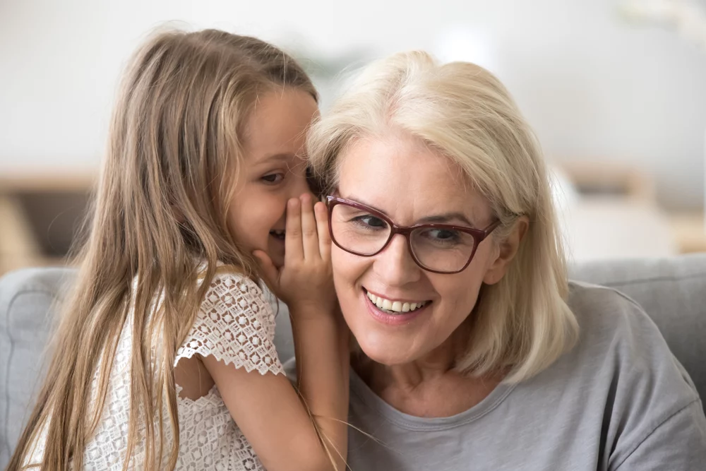 Granddaughter whispering in grandmothers ear