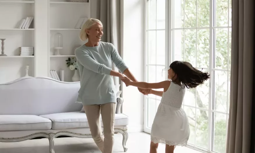 Grandmother dancing with granddaughter in living room