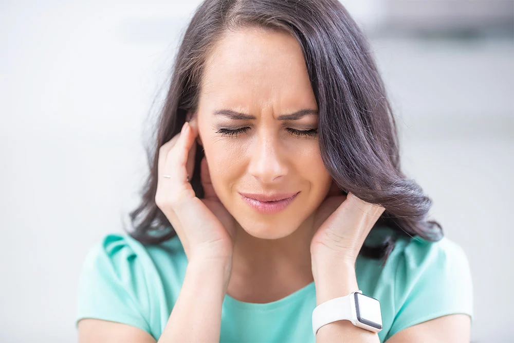 Discomforted woman holding hands to ears