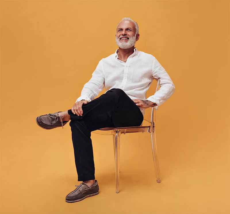 Smiling senior man sitting in chair with legs crossed