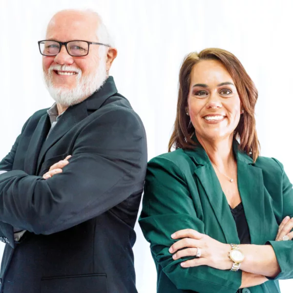 Two staff members smiling with arms crossed