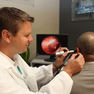 Audiologist examining patient's ear with otoscope