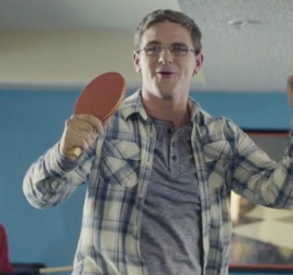 Young man with glasses holding ping pong paddle