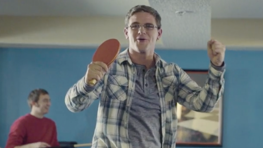 Young man with glasses holding ping pong paddle
