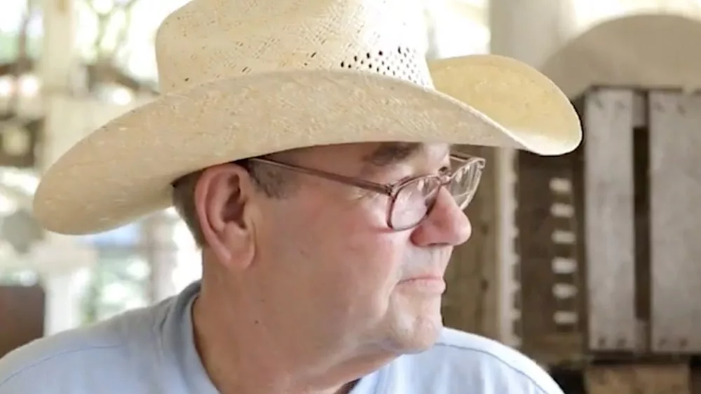 Side profile of elderly man wearing glasses and a cowboy hat and hearing aids