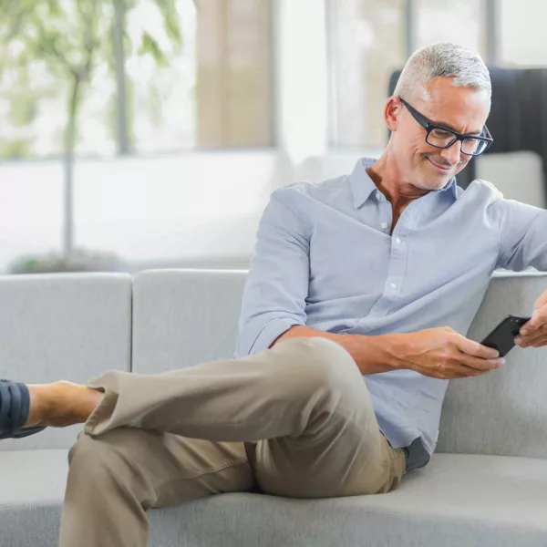 Man on couch smiling at phone