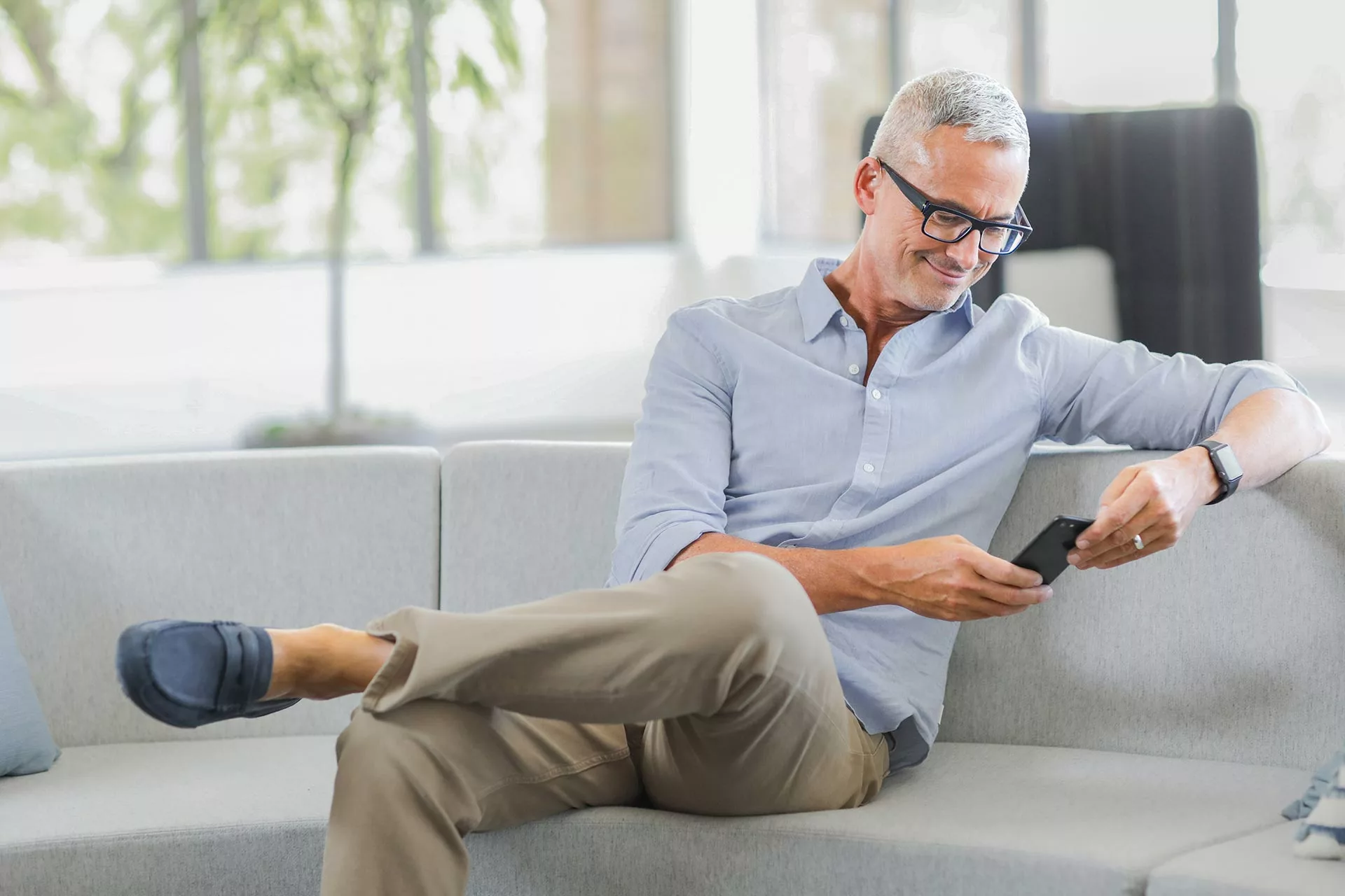 Man on couch smiling at phone