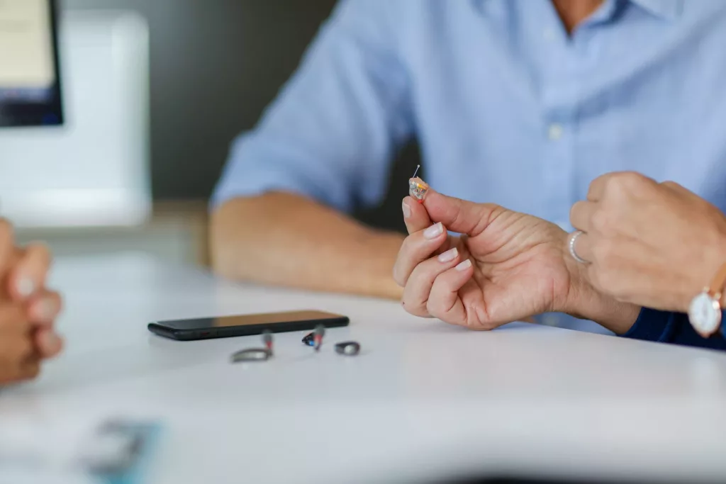 Close up of person holding hearing aid in hand