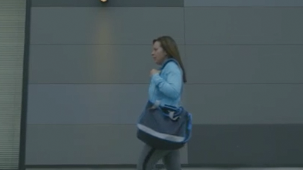 Woman carrying a bag and wearing athletic clothing walking down the street