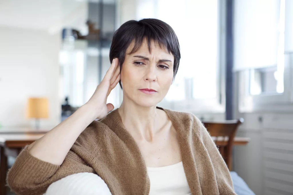 Woman in discomfort, holding a hand up to her head