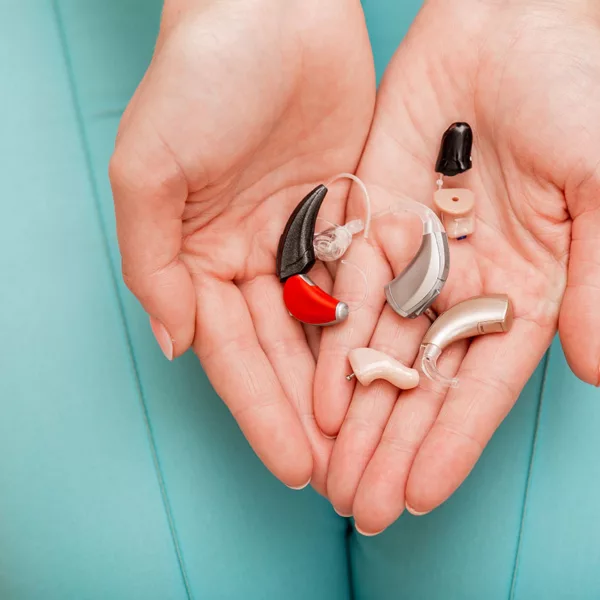 Various types of hearing aids in a woman's hands over her lap