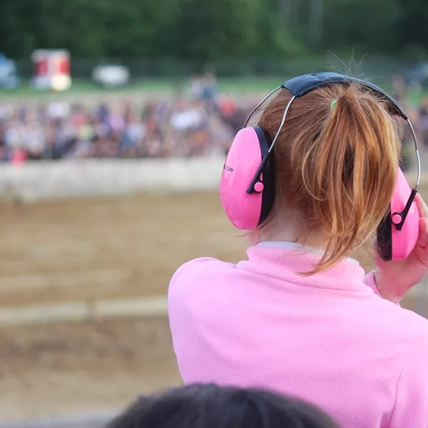 A young women wearing ear muffs to protect her hearing while at a loud event