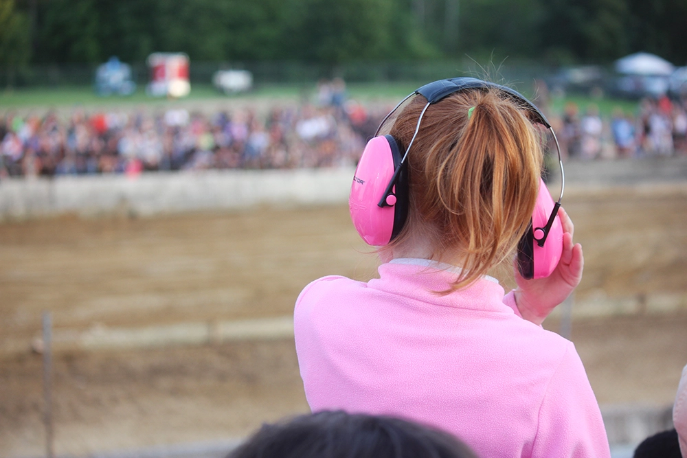A young women wearing ear muffs to protect her hearing while at a loud event