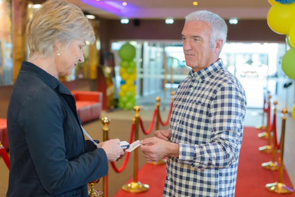 man proffering ticket to usher in empty lobby