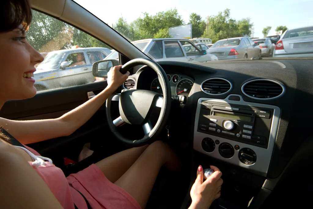young woman listening to the radio at an acceptable volume while sitting in traffic