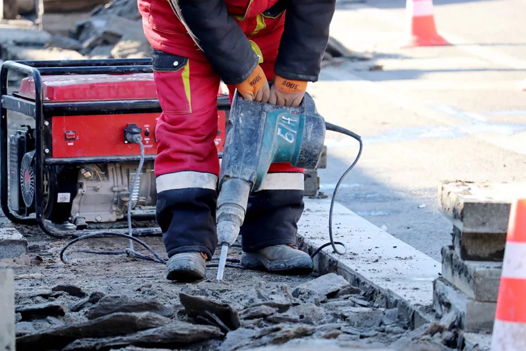 Workman's arms and legs while using jack hammer on city street.