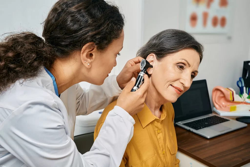 Older woman during hearing exam with younger audiologist