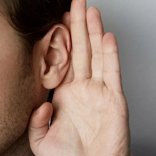 close up of man with sideburns and short hair with eyes closed and hand held behind ear