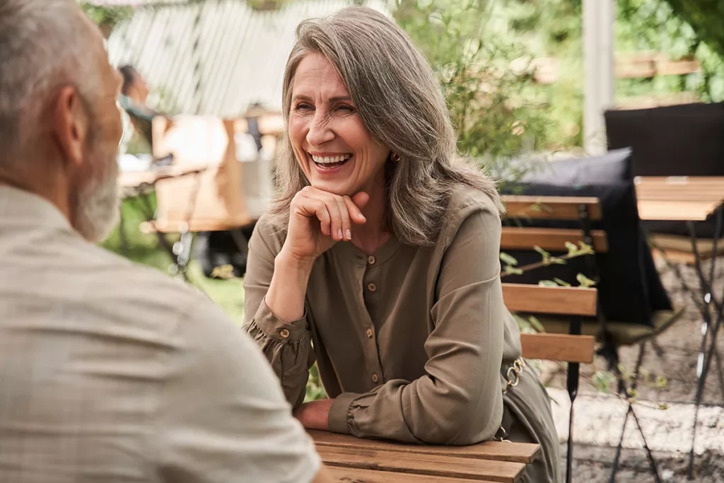 Two older adults sitting outside at a cafe enjoying a pleasent conversation 