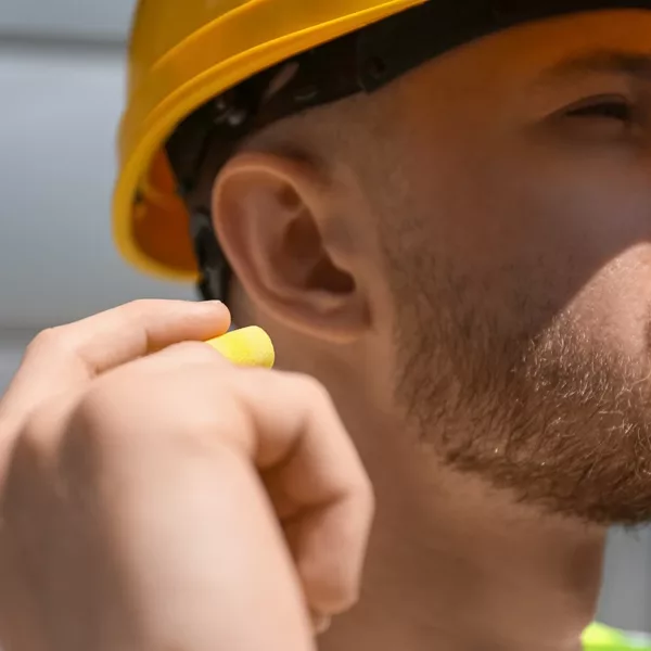 Male worker putting ear plug outdoors, closeup
