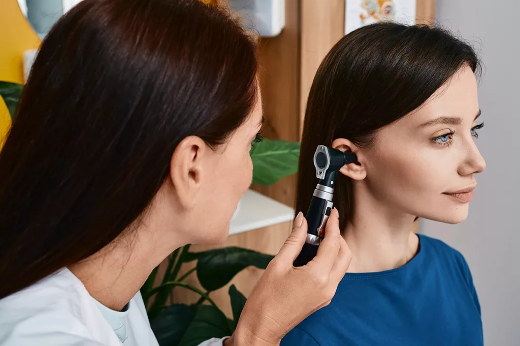 An adult woman getting a routine hearing check-up performed by a hearing specialist 