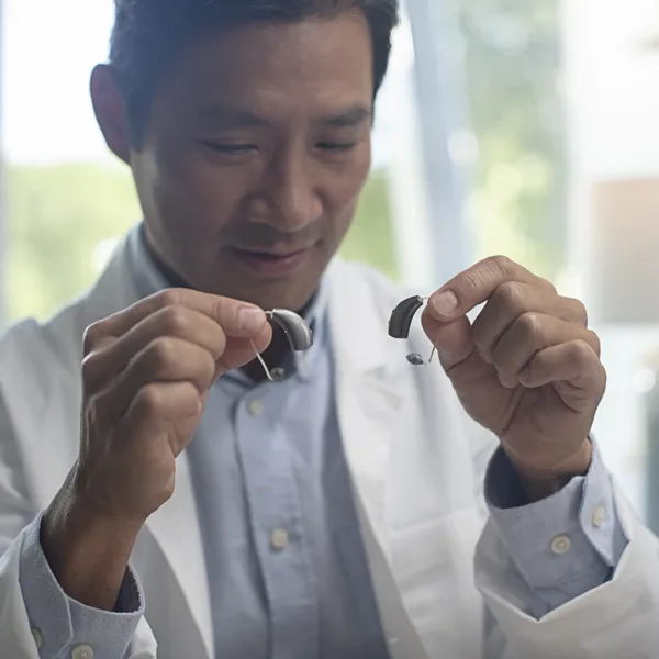 A hearing care specialist holding up two different behind-the-ear BTE hearing aids