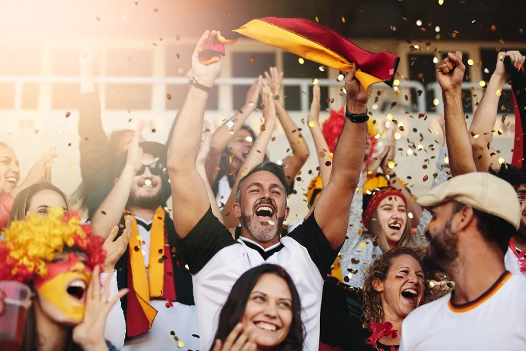 A group of sports fan loudly cheering on their team at an event