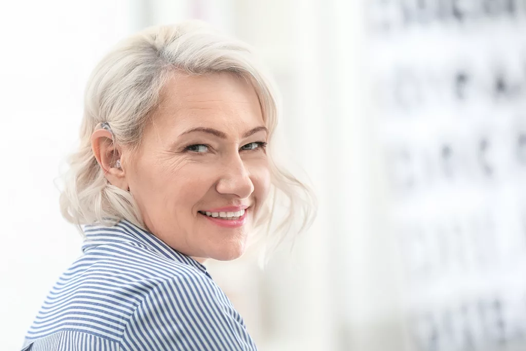 A mature women wearing a hearing aid for the first time and smiling