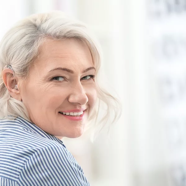A mature women wearing a hearing aid for the first time and smiling