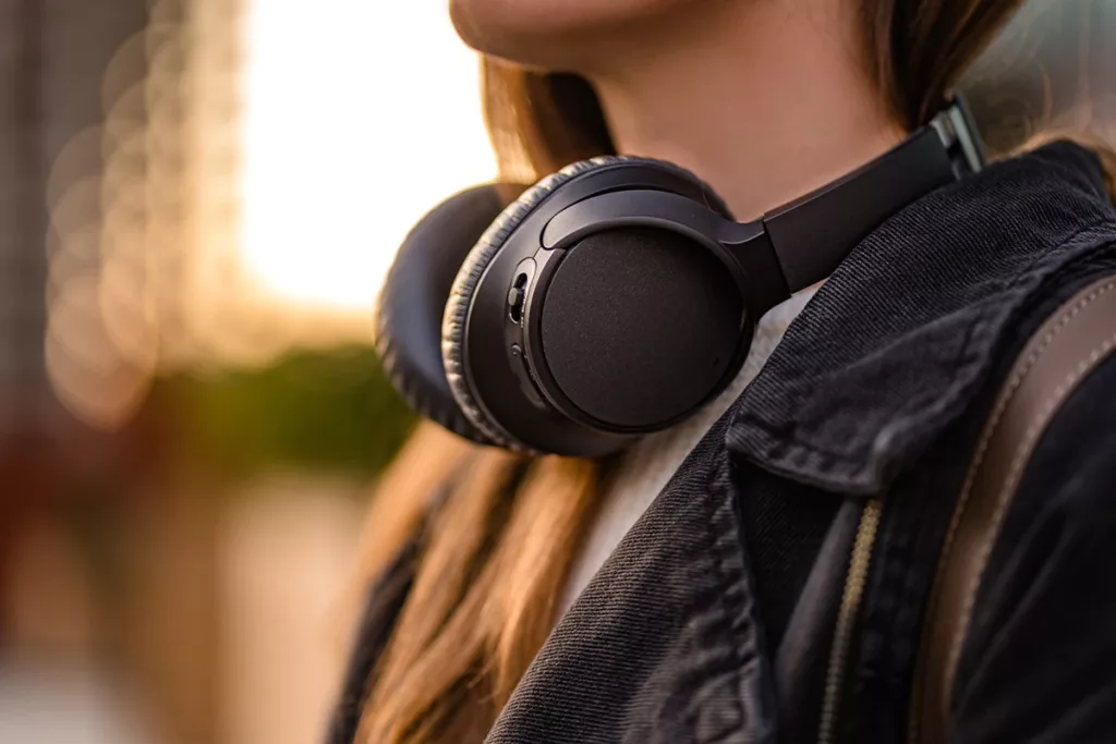 Women with black wireless noise-canceling headphones walking around the city.