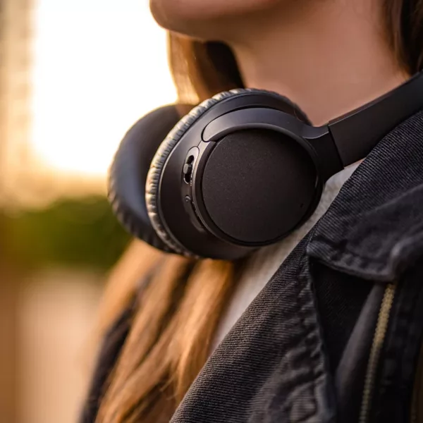 Women with black wireless noise-canceling headphones walking around the city.