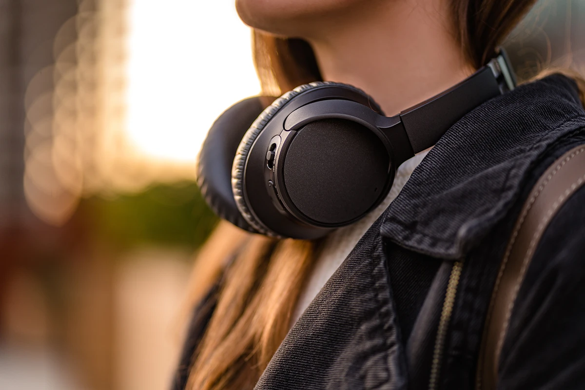 Women with black wireless noise-canceling headphones walking around the city.