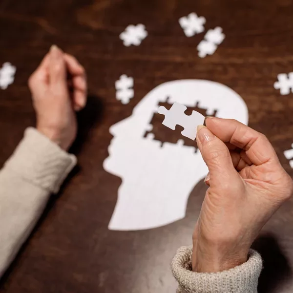 Older adult women doing a puzzle in the shape of a human brain, symbolizing the connection between hearing loss and dementia.