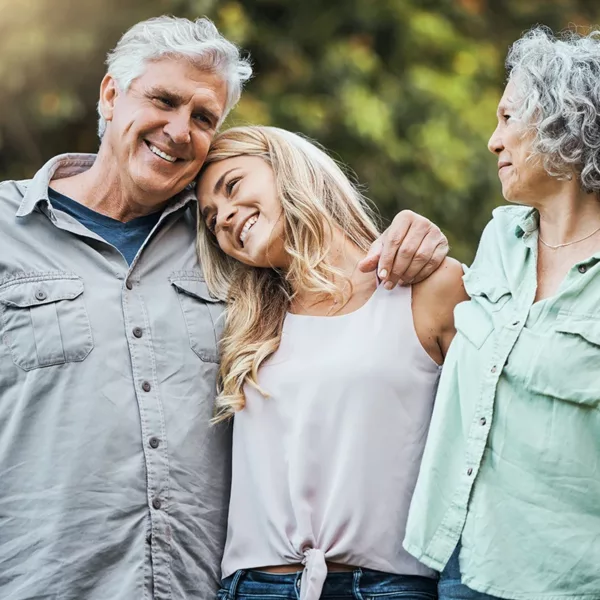 An adult daughter loving hugging her senior aged mother and father while enjoying time together as a family, symbolizing caring for a loved one with hearing loss