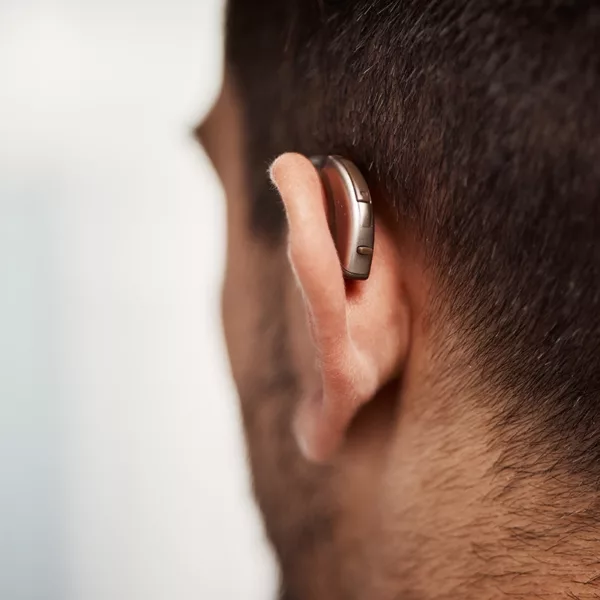 A close up of a middle aged man wearing a discreet behind-the-ear hearing aid