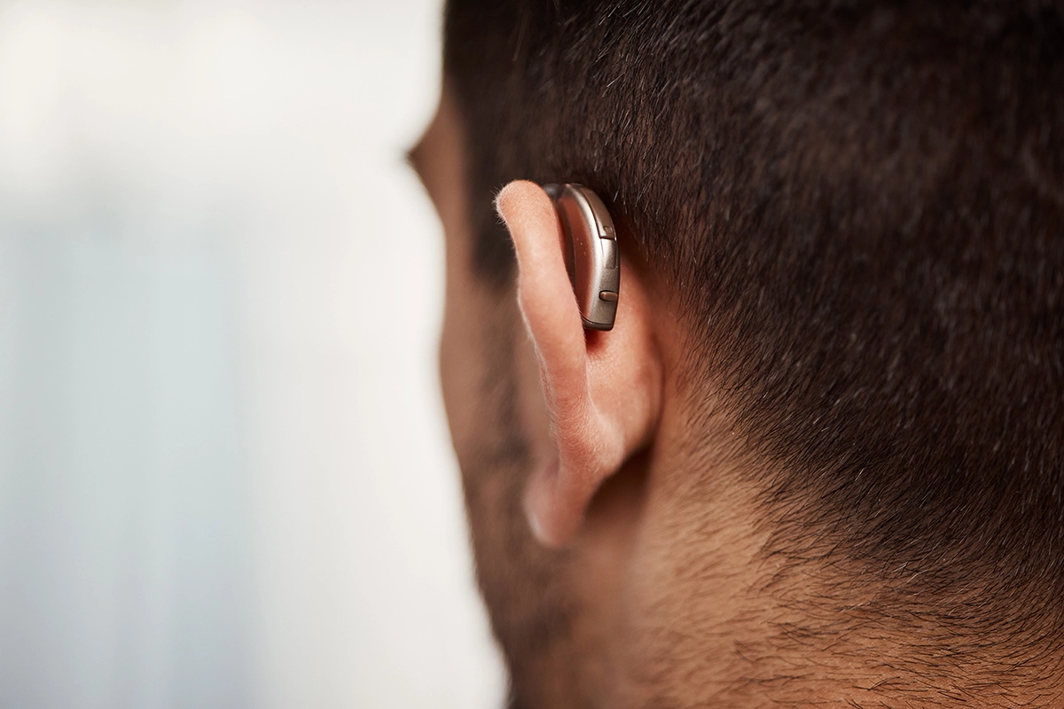 A close up of a middle aged man wearing a discreet behind-the-ear hearing aid