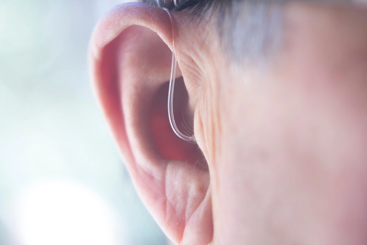 Older man wearing behind the ear hearing aid; concept for hearing loss treatment