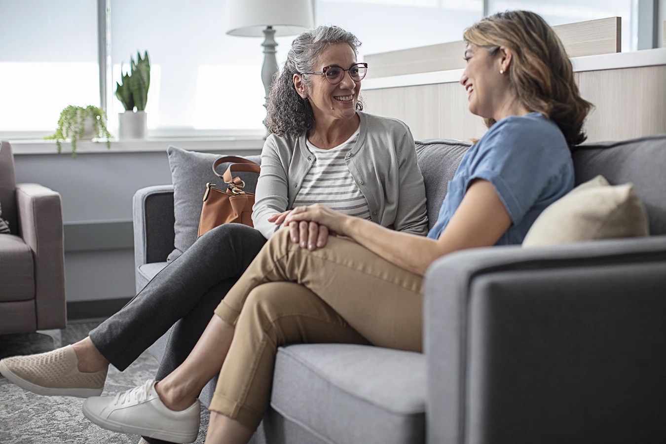 Two women sitting on a couch happily chatting together