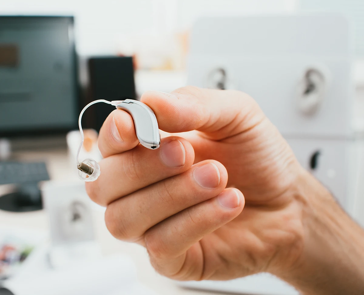 BTE hearing aid close-up in a male hand. Hearing solution, man holds a hearing aid