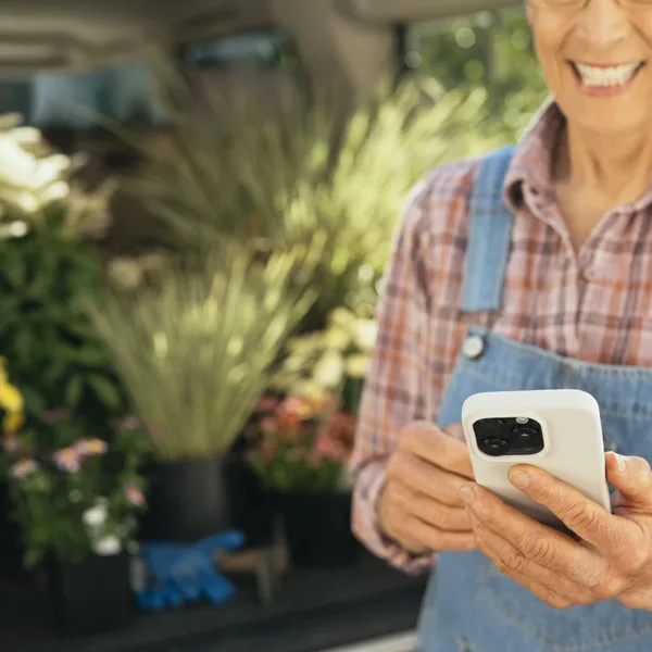 A hearing aid wearer looking down at their smartphone as they use their hearing aid app to optimize their hearing aid performance while outside