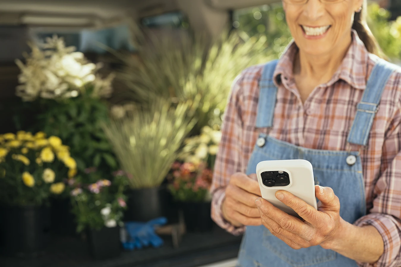 A hearing aid wearer looking down at their smartphone as they use their hearing aid app to optimize their hearing aid performance while outside