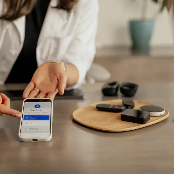 A hearing care specialists pointing to a smartphone screen explaining to a patient how a hearing aid app works.