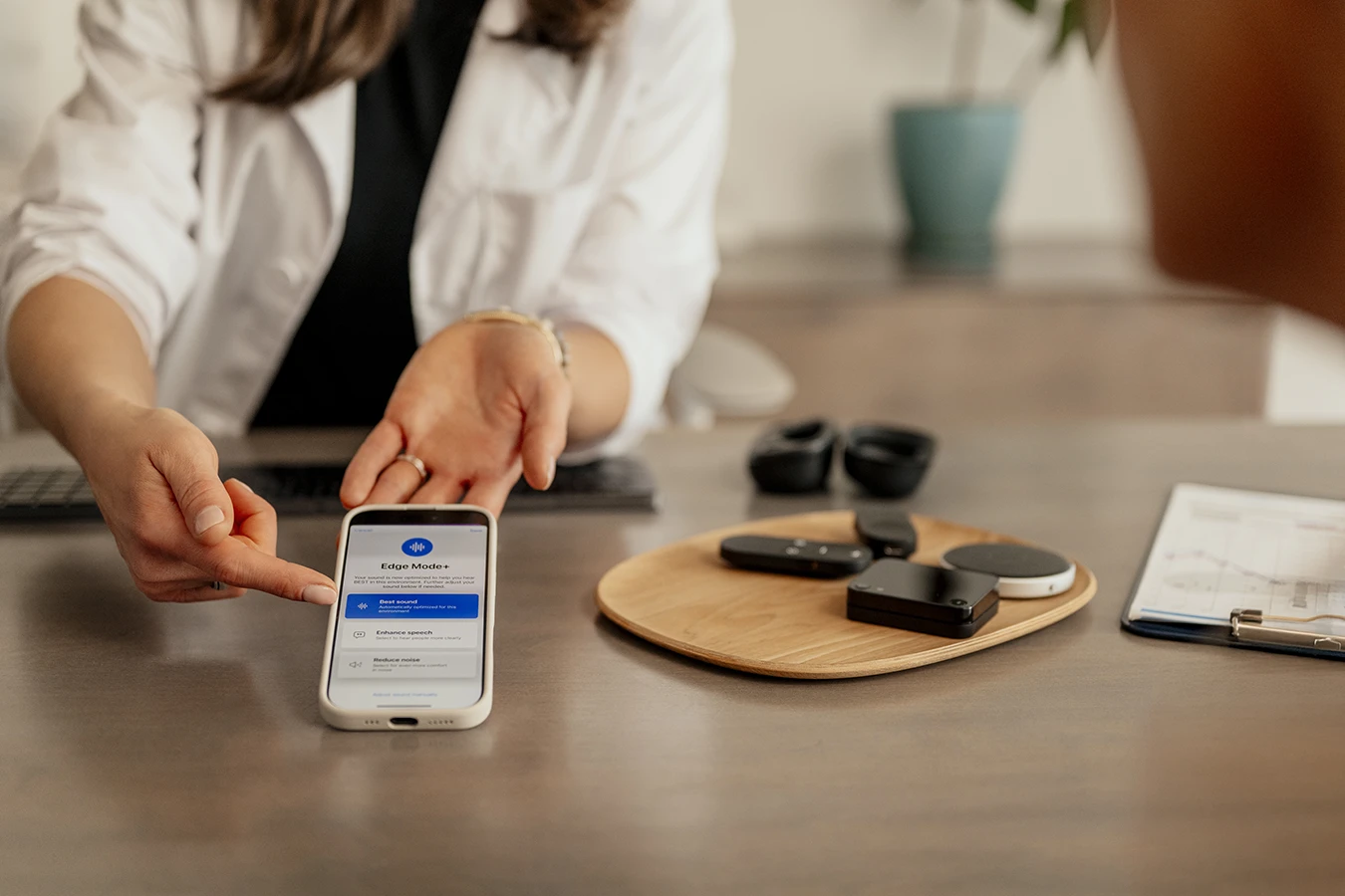 A hearing care specialists pointing to a smartphone screen explaining to a patient how a hearing aid app works.