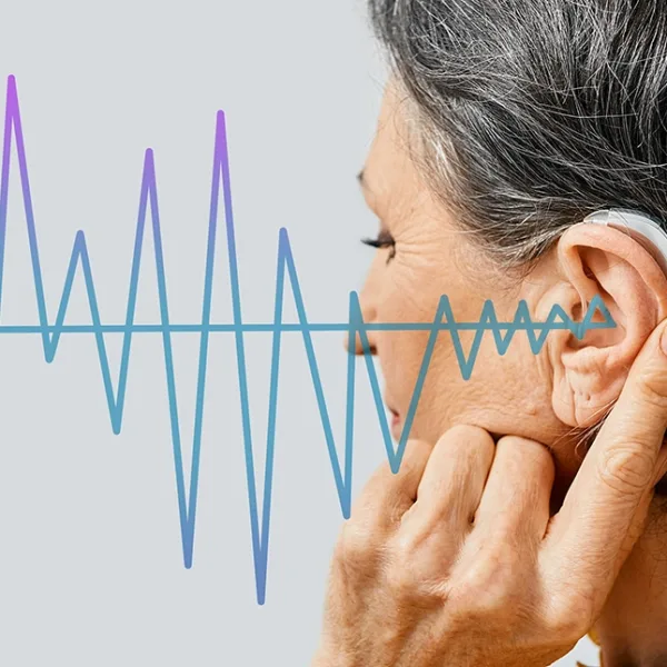 Mature woman with hearing aid on light background, closeup