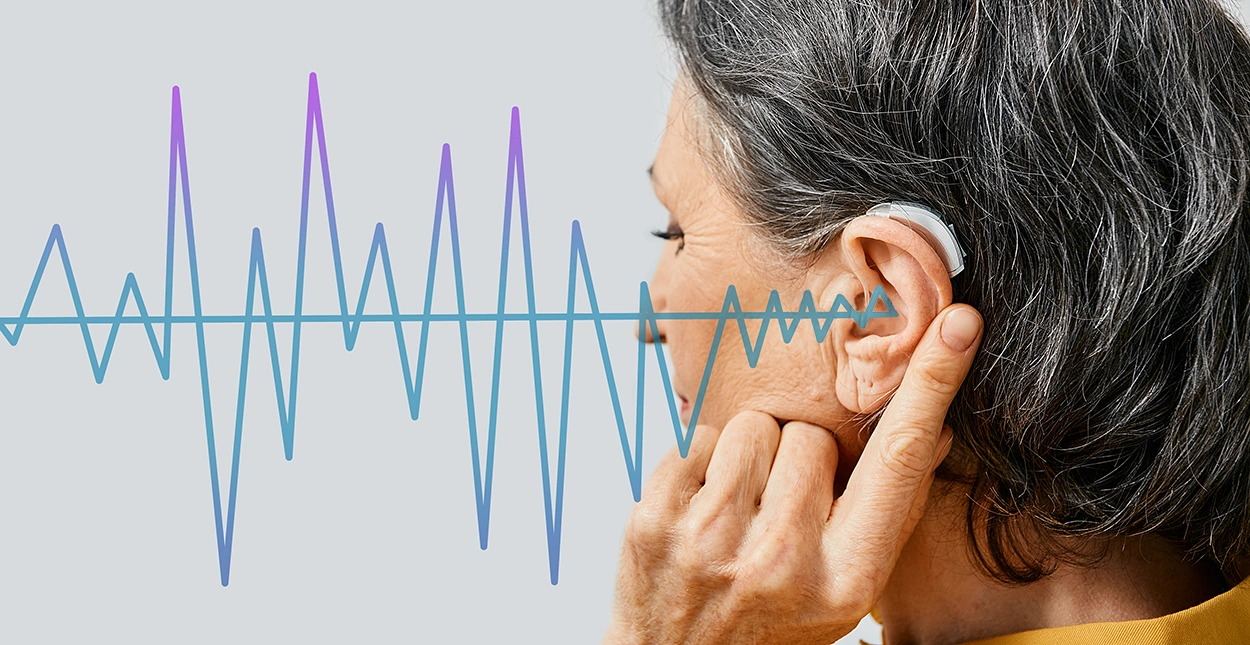 Mature woman with hearing aid on light background, closeup