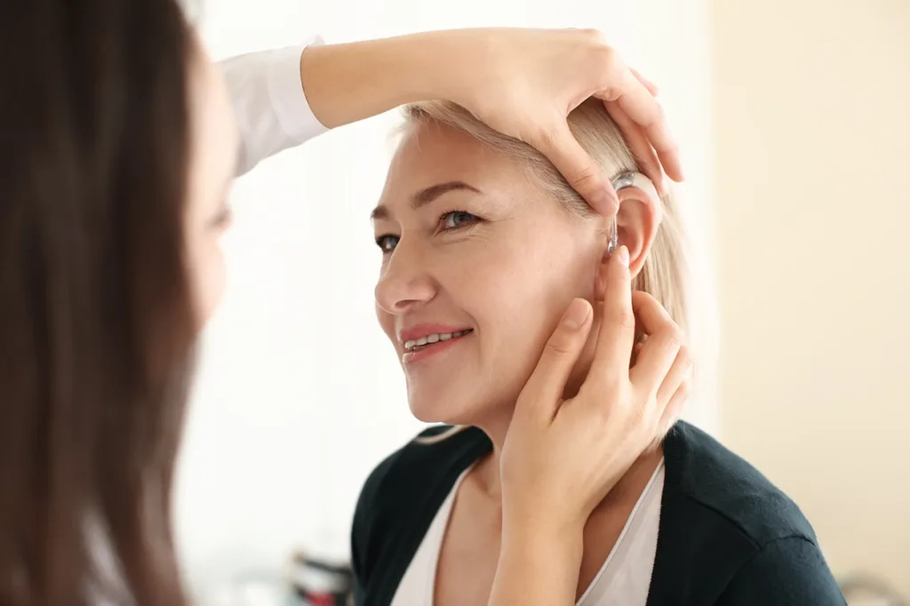 Hearing Care Specialist placing a hearing aid in a patient's ear after programming it to their hearing profile