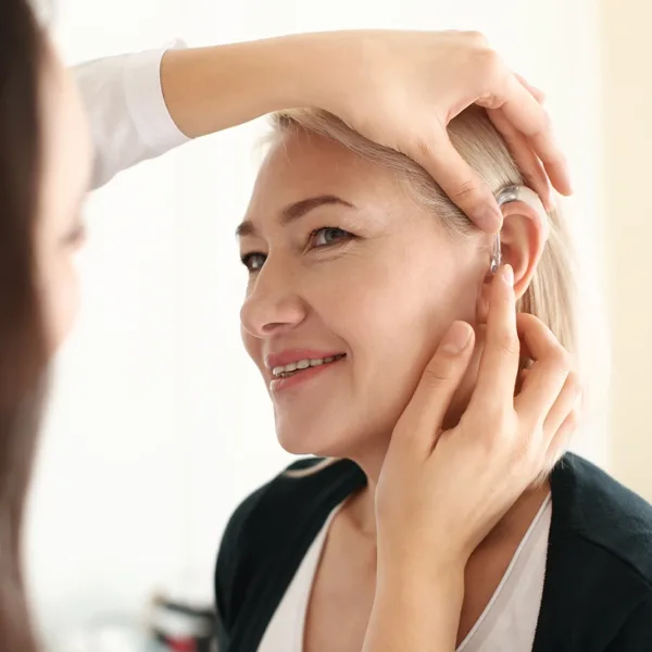 Hearing Care Specialist placing a hearing aid in a patient's ear after programming it to their hearing profile