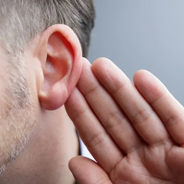 Older man holding had up to his ear indicating he is trying to hear something more clearly, age-related hearing loss symptoms