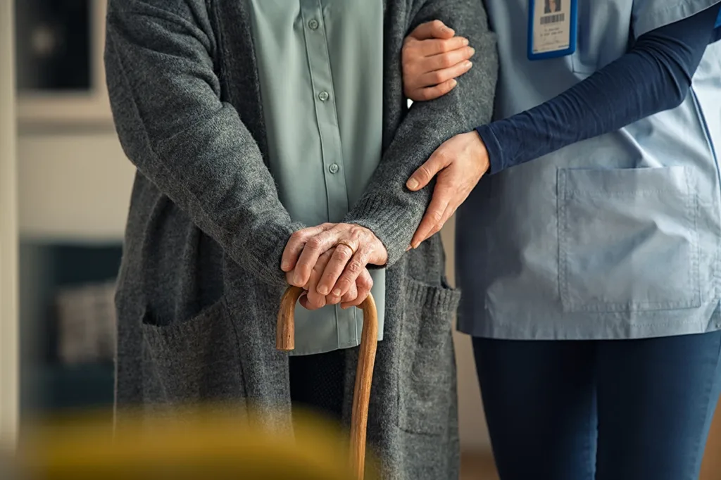 Nurse assisting an older adult walking with cane